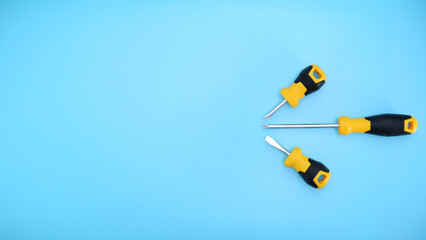 different type of yellow and black screwdrivers hand tools flat lay isolated baby blue background with copy space 