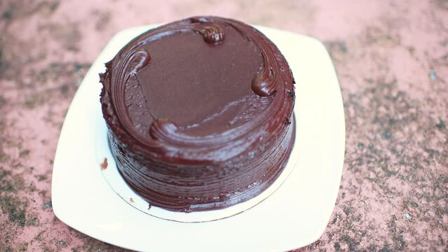 Macro closeup of dark chocolate layered layers rich decadent fudge cake made of buttermilk or buttercream on white plate with rack focus