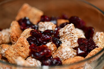 Breakfast cereal with dried cranberries in a glass bowl.