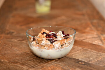 Breakfast cereal with dried cranberries in a glass bowl.