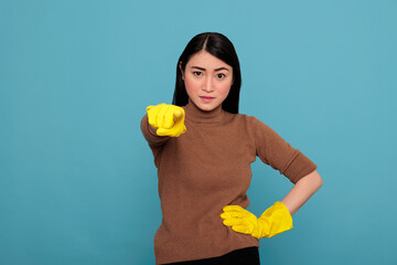 Tired frustrated and unhappy asian housewife pointing finger to the front wearing yellow gloves,...