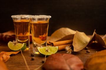 Tequila, shots with autumn decoration, with dry leaves on wooden table