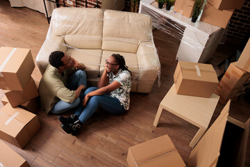 Young homeowners dreaming about apartment decor, moving in rented household flat and sitting...