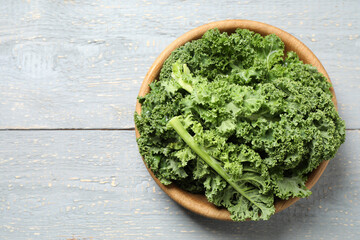 Fresh kale leaves on light grey wooden table, top view. Space for text
