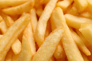 Many delicious French fry pieces as background, closeup