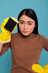 Confidence serious asian young houseworker from chores wearing yellow gloves holding a sponge, Cleaning home concept, Faithful tired and overwhelmed housework housewife from day to day chores