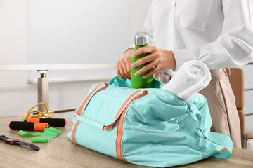 Businesswoman packing sports stuff for training into bag in office, closeup