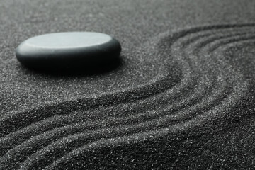 Zen garden stone on black sand with pattern, closeup