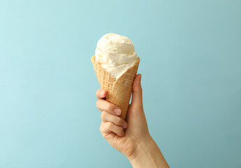 Woman holding waffle cone with delicious ice cream on light blue background, closeup - Powered by Adobe