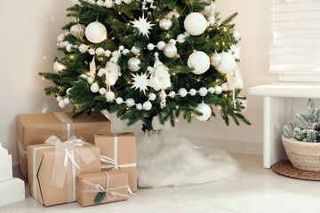 Decorated Christmas tree with faux fur skirt and gift boxes indoors, closeup