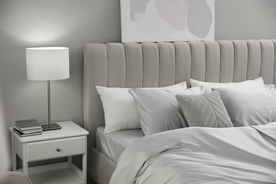 Cozy bed with soft silky bedclothes in light room