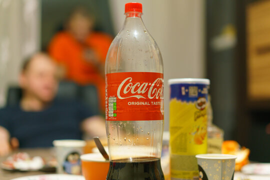 2 liters plastic bottle of Coca-Cola stands on a table at the party. Red. Editorial. Bubble. Pop. List. Refreshing. Nutrition. Restaurant. Waste. Calories. Cooler. Ingredients. Junk Food. Nutrient.