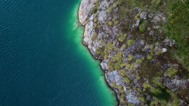 Bird's eye view of a turquoise green water lake shore at Lake Quilotoa in Ecuador