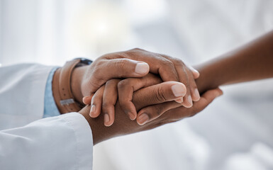 Support, trust and hospital care with a doctor and patient holding hands, sharing bad news of a...