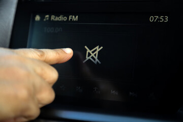 Press the mute button on the car audio. finger touching touch screen on car audio to muting radio...
