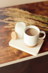 Autumn cozy composition. A cup of coffee, a plaid, a candle, dried flowers on a light background. Autumn, fall concept.