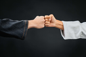 Teamwork, respect and discipline with hands fist bumping before a fight, match or mma competition. Closeup of two athletes greeting before combat sport and self defense against a black background - obrazy, fototapety, plakaty