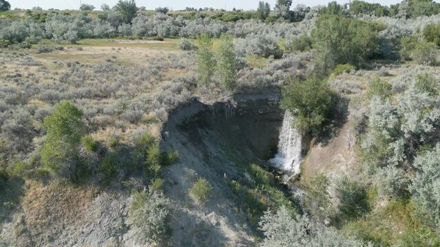 Waterfall drone aerial still stationary 4k footage in Wyoming with green trees with water falling into Shoshone river