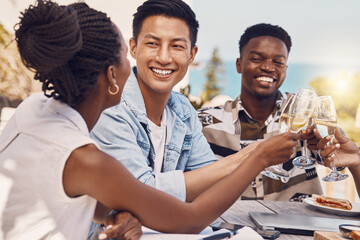 Diverse group toasting and celebrating friendship at an outdoor restaurant, having fun and laughing. Happy people cheers while bonding, talking and enjoying a celebration of good, exciting news