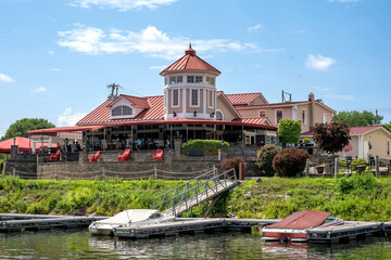 Fototapeta na wymiar Schenectady, NY – USA - Aug 5, 2022 Waterfront view of the The Water’s Edge Lighthouse Restaurant, a 19th-century farmhouse turned into an American eatery with a cabana bar set along the Mohawk River.