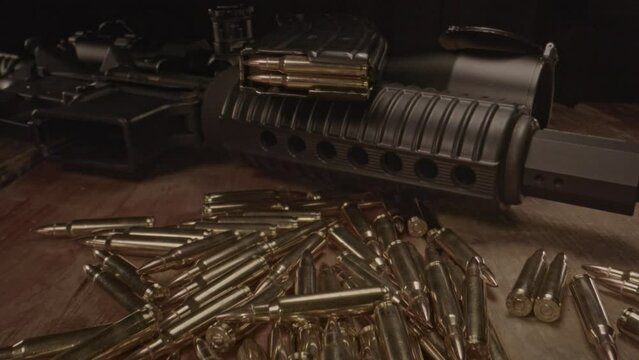 Beautiful dolly in over .223 ammo towards loaded magazine on top of an AR-15 assault rifle
