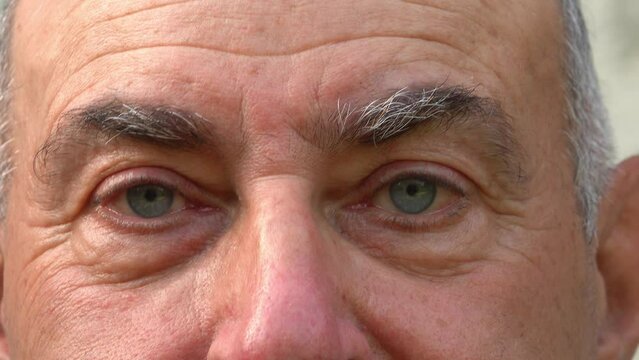 The upper part of the face of a balding middle-aged man with wrinkles on his forehead and blue eyes.