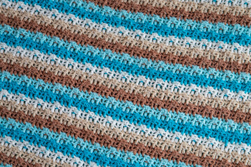 close-up of grandma's crocheted or knitted blue, tan, brown, and white striped blanket, this blanket makes you think of grandma's house, it is cozy and warm