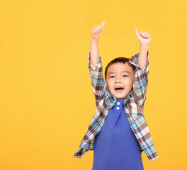Happy asian boy in front of yellow background and showing thumbs up