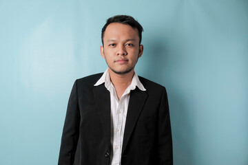 Cool businessman wearing black suit standing on blue background