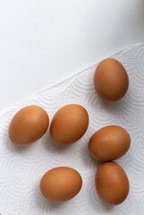 Fresh raw organic chicken eggs on white tissue paper, top view