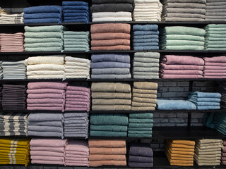 Multicolor towels on shelf in market, sale cotton towels, stack colored cotton towels, a shelf in the home row of the market, close-up selective focus