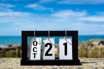 Oct 21 calendar date text on wooden frame with blurred background of ocean.