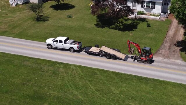 a small businessman loads up construction equipment to the trailer by truck