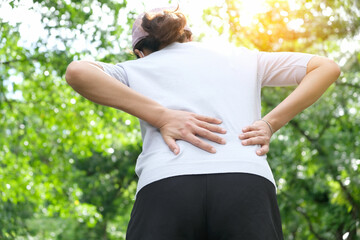 Woman's hand She is caught at the waist and her back is painful at the back in the park. Cause of...