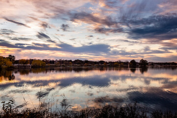 Dramatic pink and purple sunset clouds reflection on Woodlawn Lake San Antonio Texas