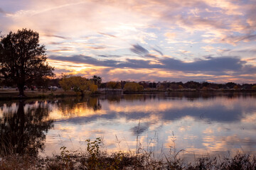 Fototapeta na wymiar Dramatic pink and purple sunset clouds reflection on Woodlawn Lake San Antonio Texas