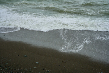 Sea shore with pebbles, wet sea pebbles on the beach and quiet sea surf