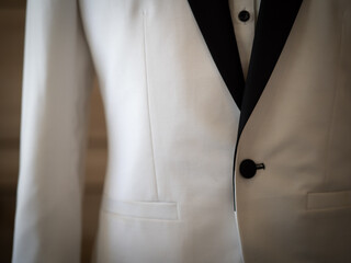 Close up of white tuxedo suit with white shirt, black button and black handkerchief