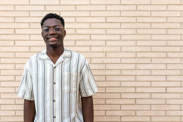 Portrait of confident young african american man outdoors. Brick wall background. Copy space.