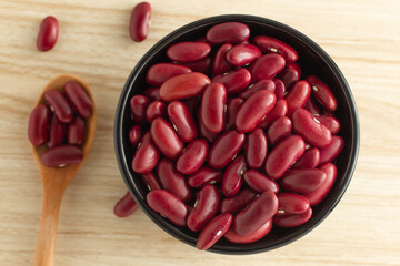 red kidney beans in a black bowl and spoon on wooden background, top view, flat lay, top-down, selective focus.copy space.