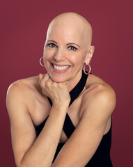 Pretty smiling middle aged over 50 woman survivor with alopecia isolated on red background - 525464422