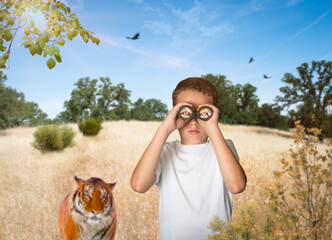 Wild animal watching young explorer boy on summer safari looking through binoculars with tiger eyes  - 525464423