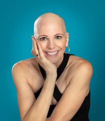 Confident mature over 50 woman survivor with alopecia sitting hand to chin isolated on blue background - 525464425