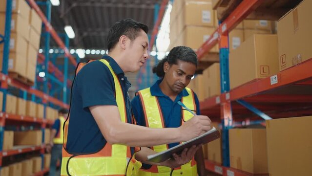 Asian two workers with list checking stock condition in business factory industry warehouse. Logistic industry concept.