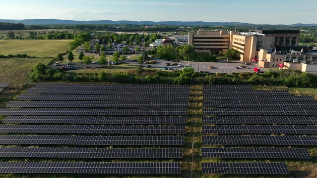 American Hospital Building With Large Solar Panel Field Array For Renewable Green Energy. Aerial Truck Shot.
