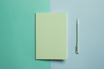Green notebook over blue background with green pen with copy space.