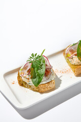 Aesthetic composition with tomato bruschetta on white background with harsh shadows. Italian bruschetta with tomatoes and cheese on fine dining in summer. Elegant menu concept.