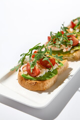 Aesthetic composition with shrimp bruschetta on white background over white wall. Italian bruschetta with shrimp, tomatoes and arugula on fine dining in summer. Elegant menu concept.