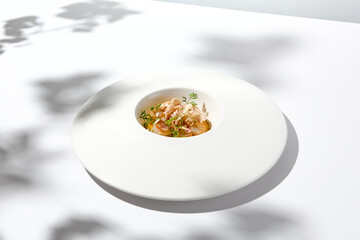 Appetizer with roasted sea scallop and cauliflower. Creamy risotto with scallops and vegetables. Grilled sea scallops in white ceramic plate with harsh shadows. Seafood menu. Summer food.