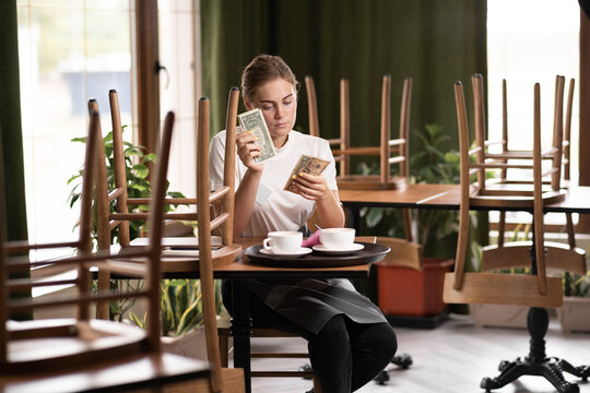 Waitress counting salary or tips in dollars while sitting in a cafe, give waiter a tip, counting money in a restaurant
